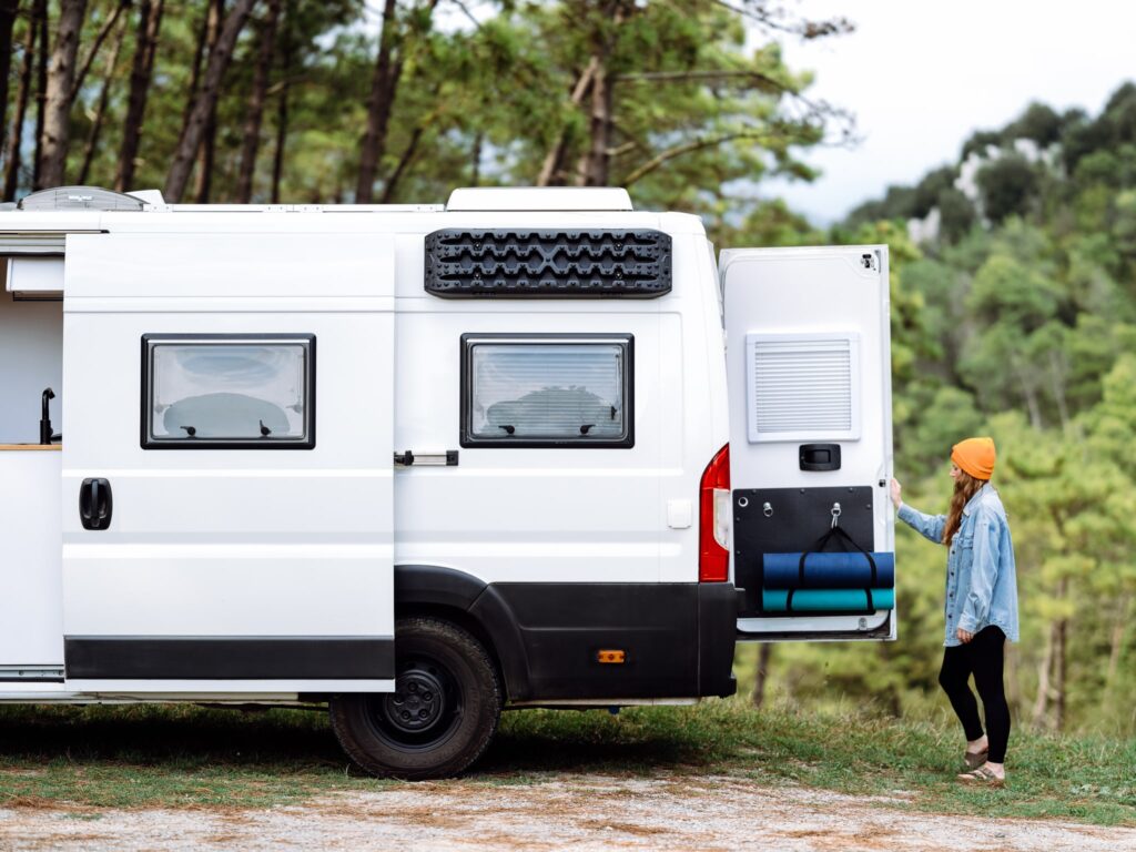 A woman opening the back door of the van giving access to the extra storage underneath the bed.